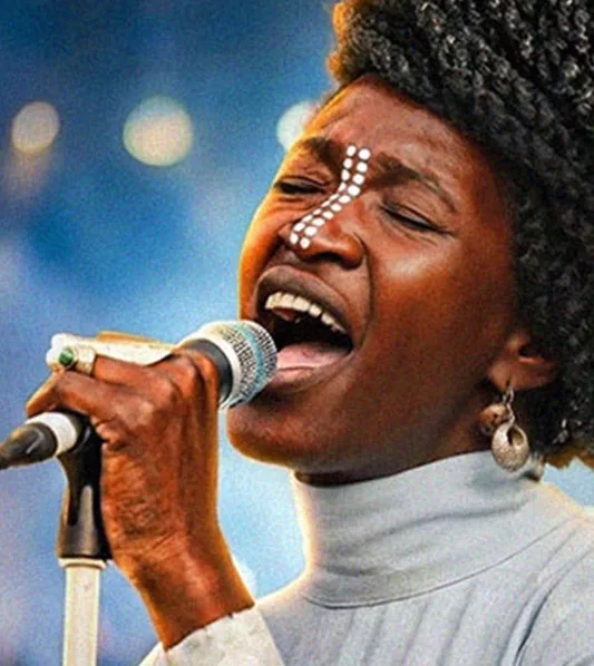 Gros plan sur la chanteuse Okali chantant avec passion au micro, visage orné de peintures tribales blanches. Portrait issu de la série d'interviews "Neo" produite par l'agence gcom en Nouvelle-Aquitaine.